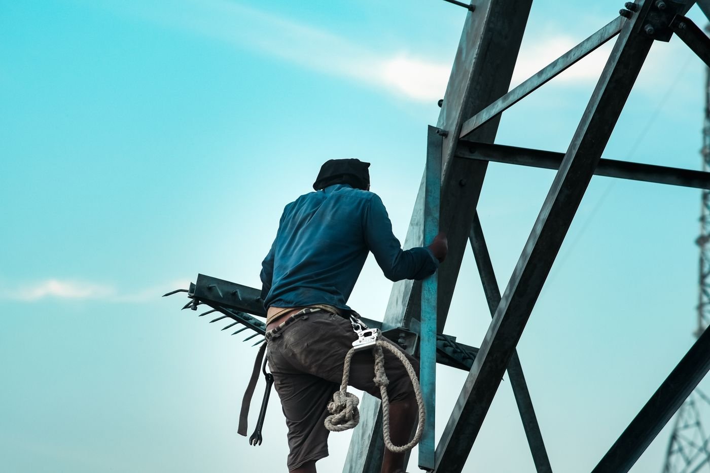 Ouvrier progressant sur une charpente métallique avec longe et connecteurs antichute