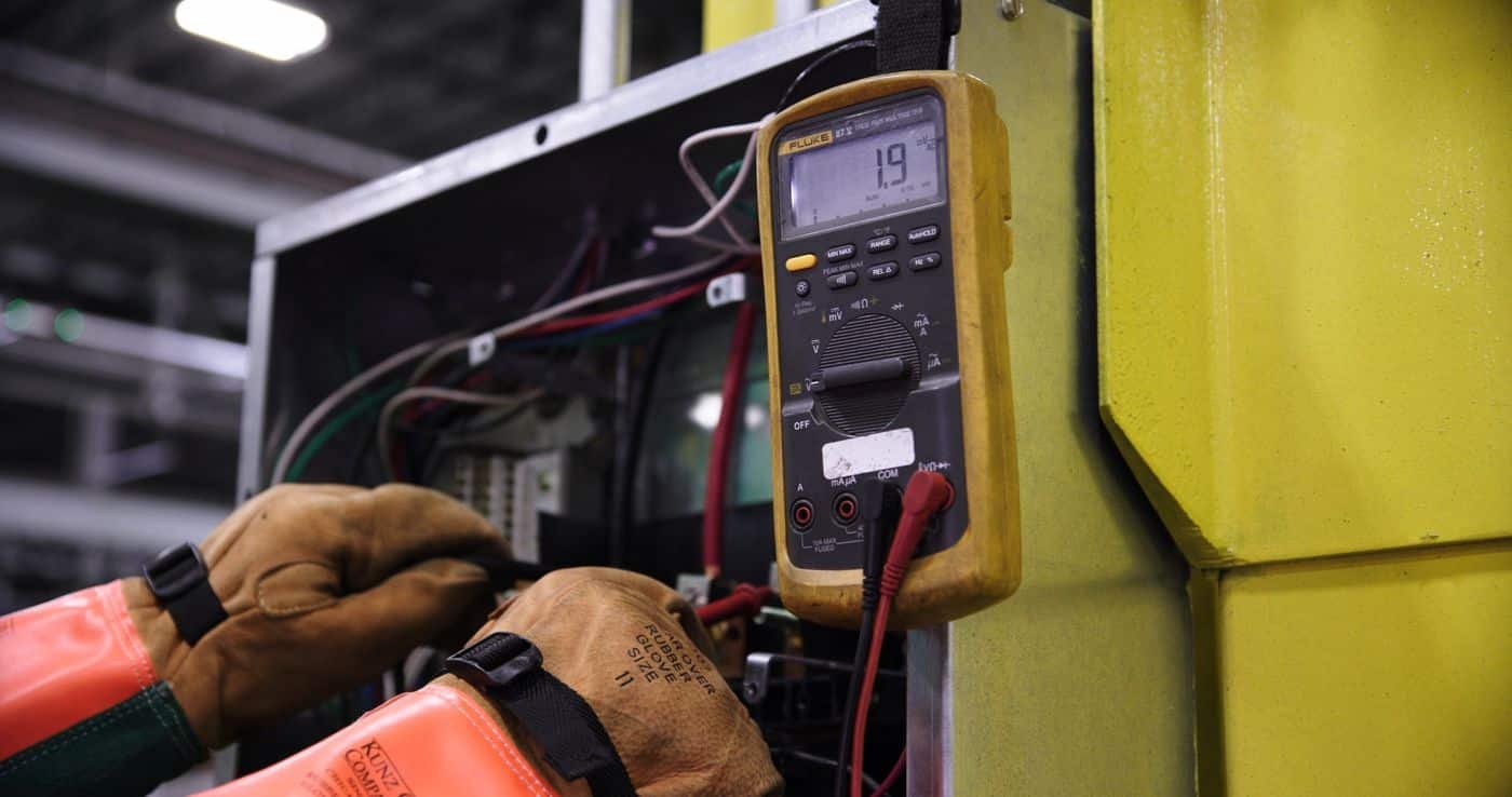 Mesure aux bornes d'un tableau avec gants isolants lors d'une vérification d'absence de tension
